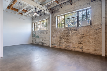 an empty room with a brick wall and a large window
